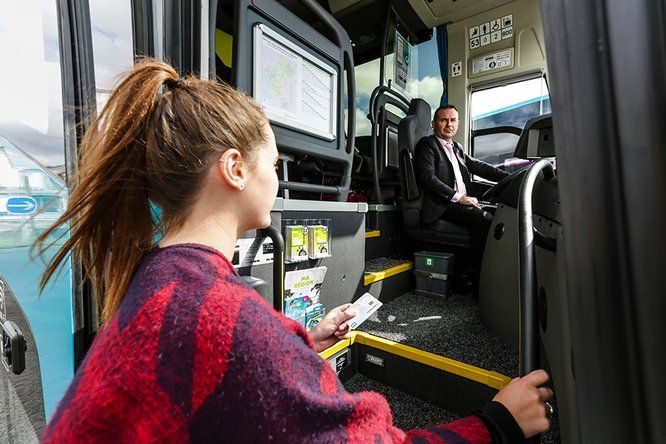 Jeune fille qui monte dans un car, le chauffeur regarde l'obejctif