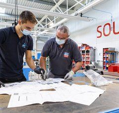 Un homme âgé et son jeune apprenti consultent des plans